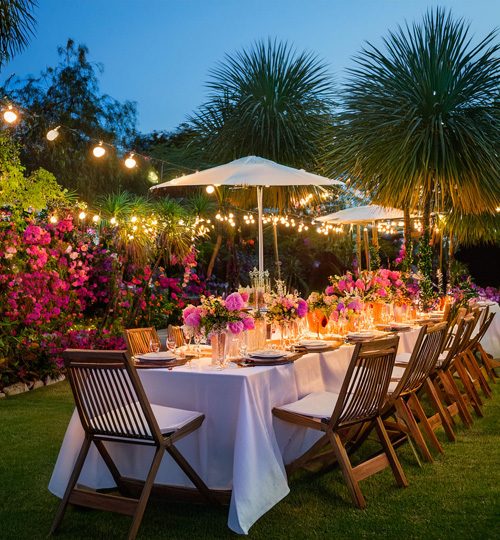 Gartendeko mit farbigen Pflanzen und Tischtafel am Abend
